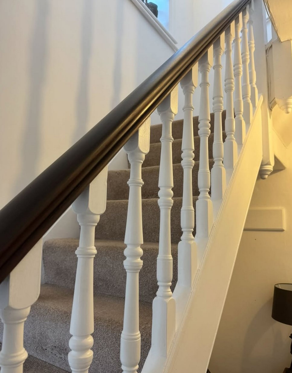 Freshly painted white staircase with a dark wood handrail