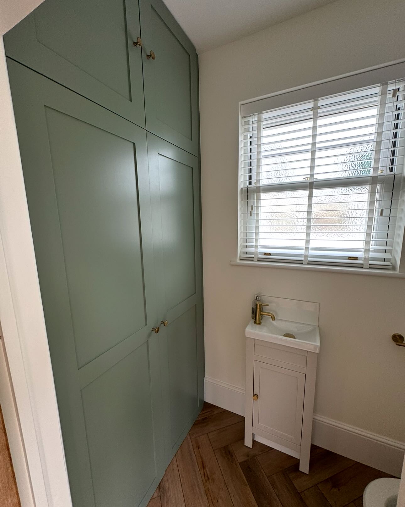 Painted green custom utility storage beside a small wash basin